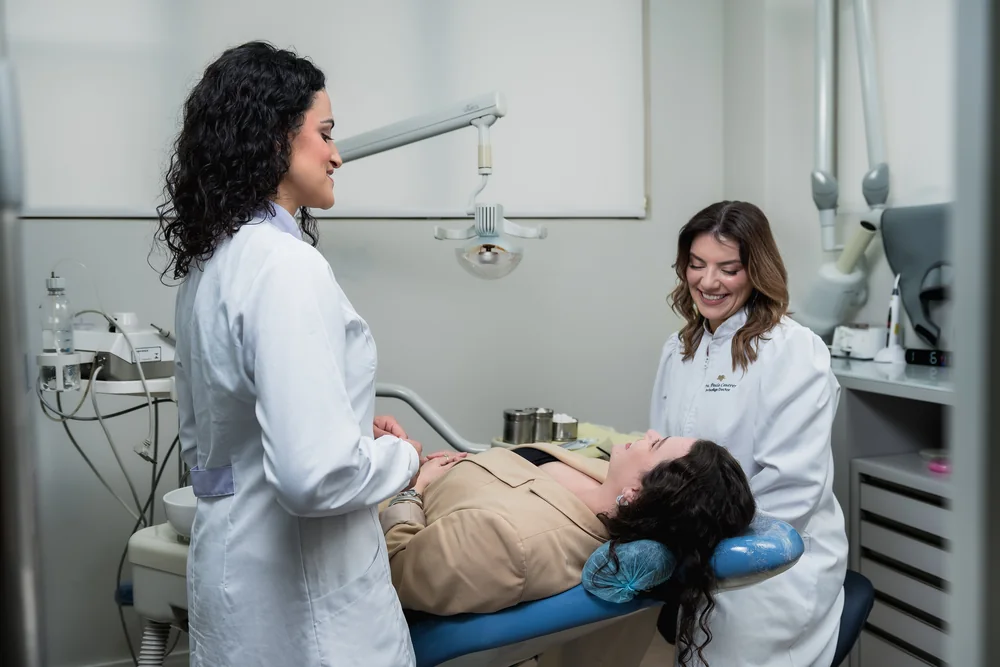 Dra. Paula e outra profissional da equipe durante o atendimento de uma paciente no consultório